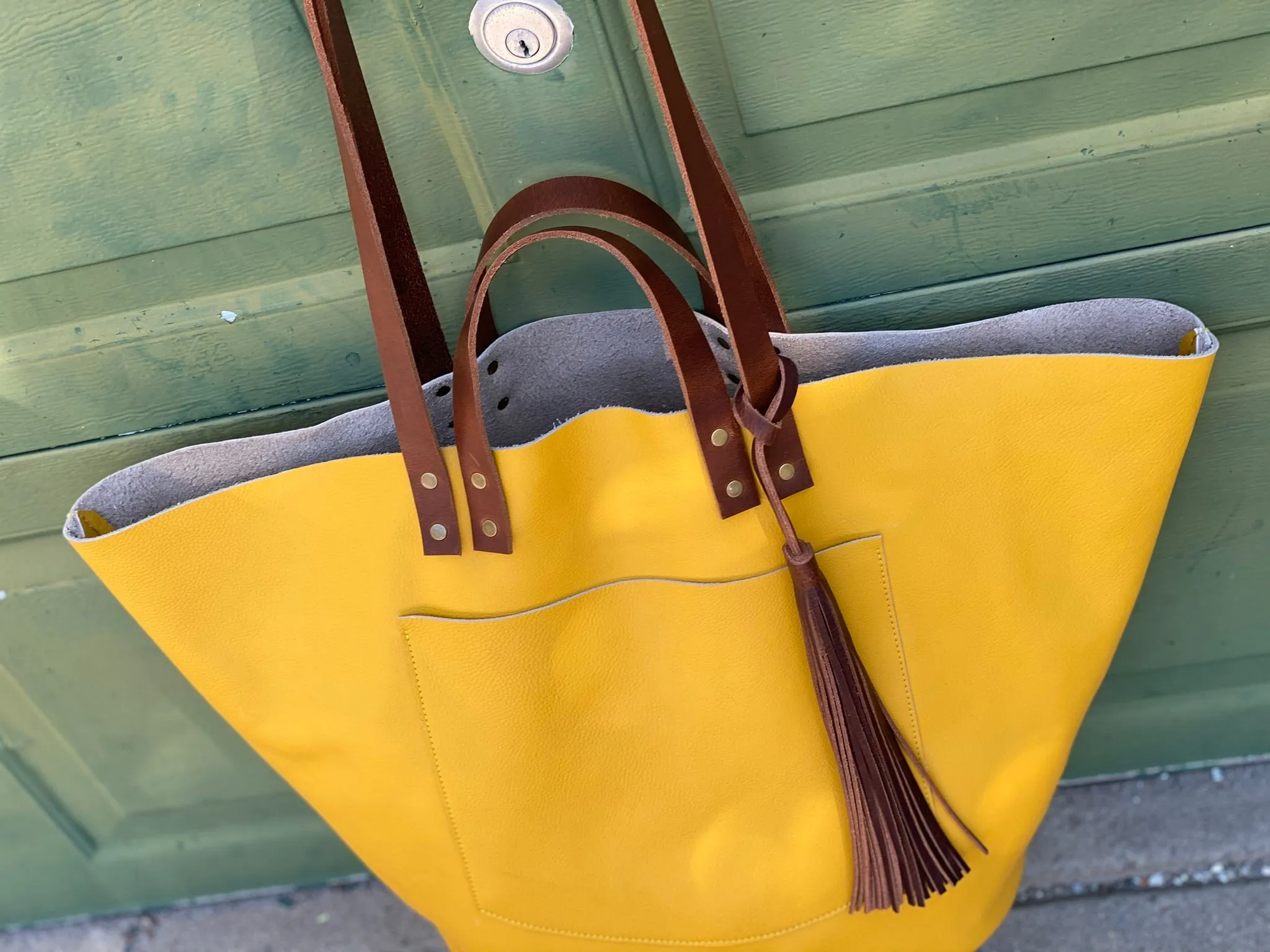 Large yellow leather tote with feather tassels