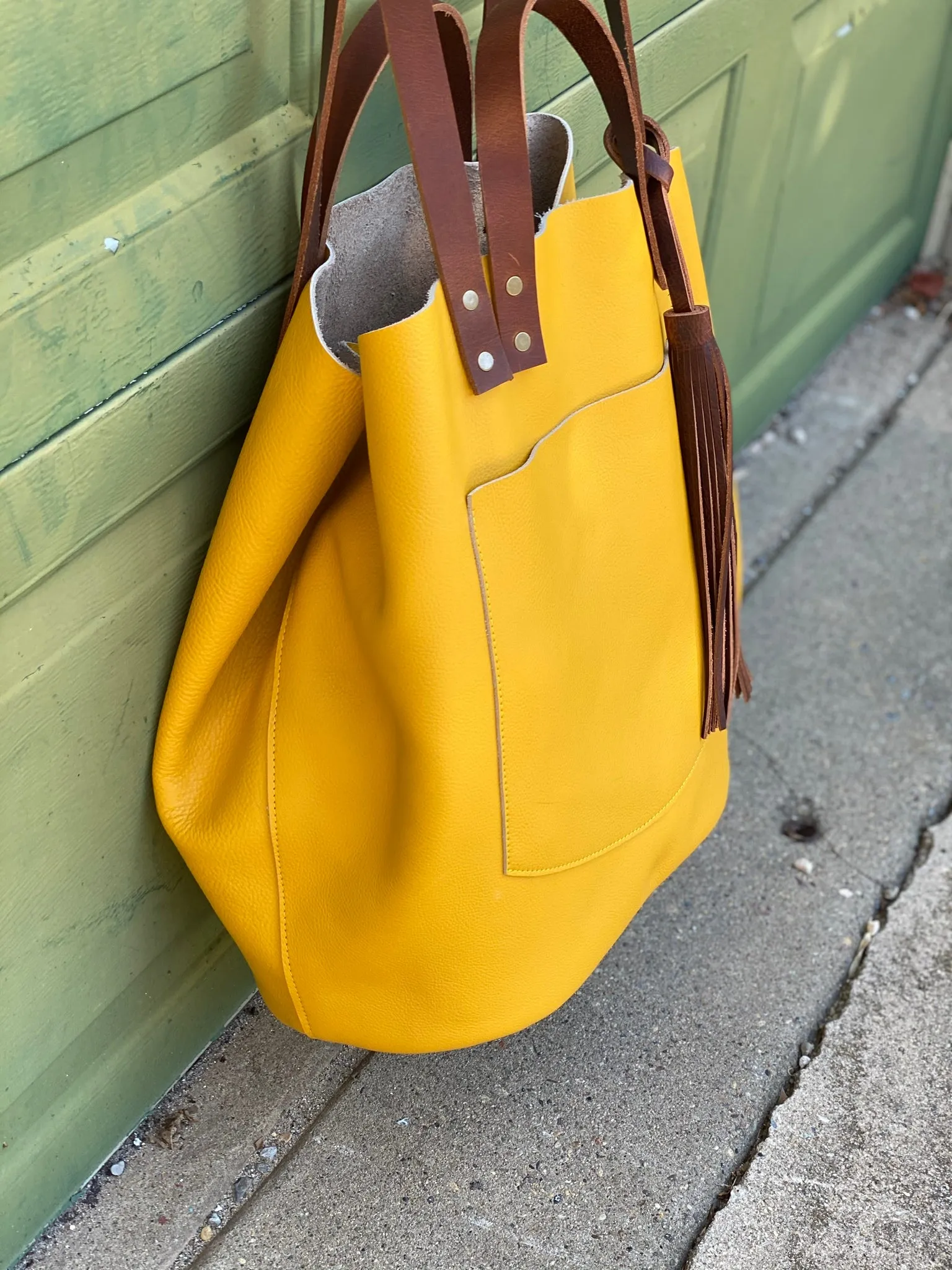 Large yellow leather tote with feather tassels